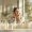 Smiling woman applying skincare products in a bright bathroom.