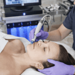 aesthetic provider performing hydrafacial skin treatment with handheld device on female patient.